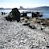 People disembarking on a boat dock near a rocky shore and mountains